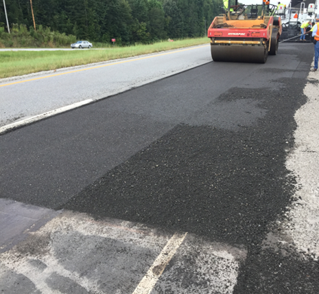 An image of a roadway where an asphalt roadway rolling machine is being used to put down the new flexible asphalt base produced using the Cold Central Plant Recycle process
